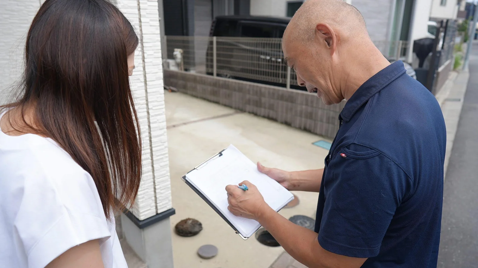 排水マスの前で書面に記入する前田信広